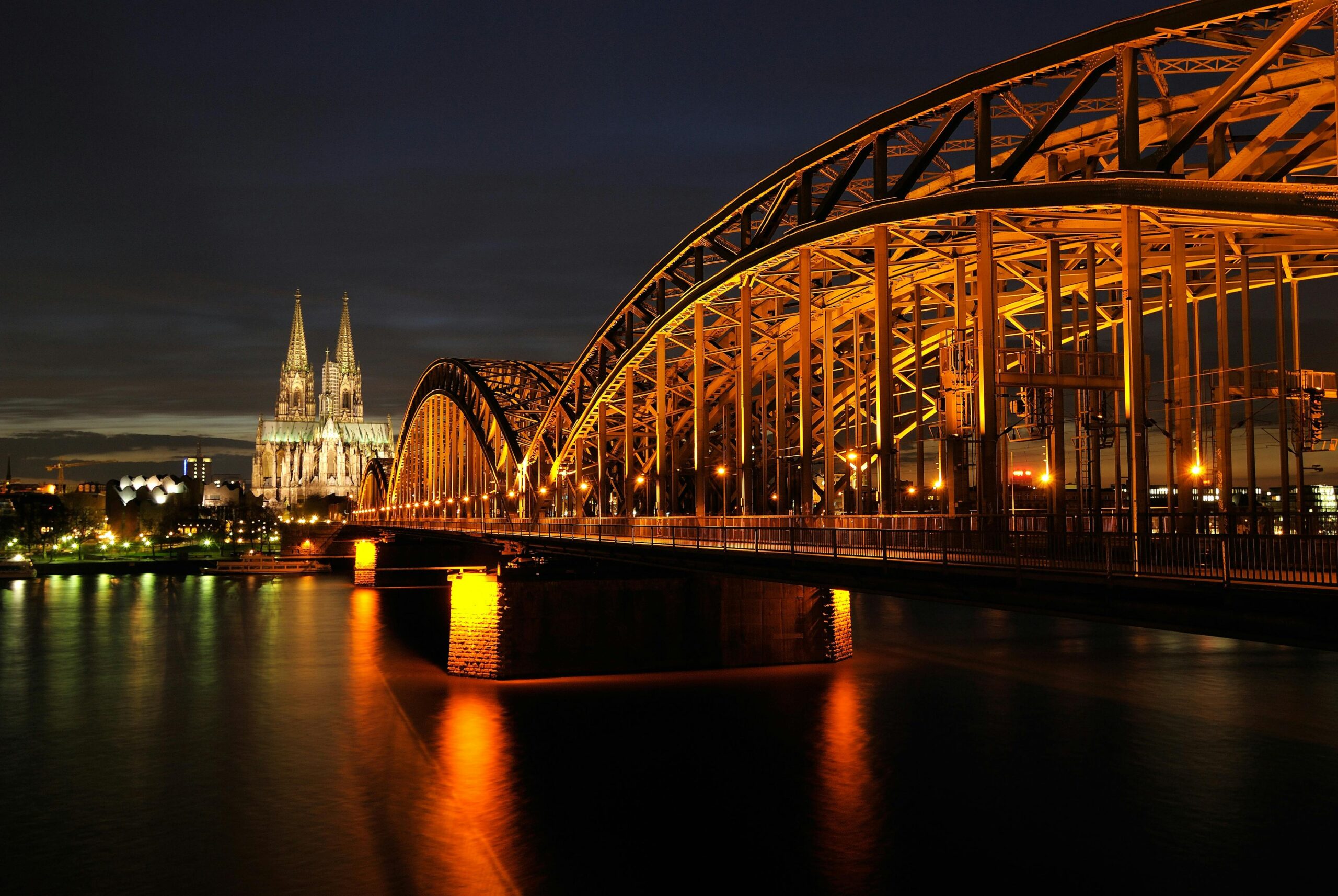 Captivating night shot of Cologne Cathedral and Hohenzollern Bridge reflected on the Rhine River.
