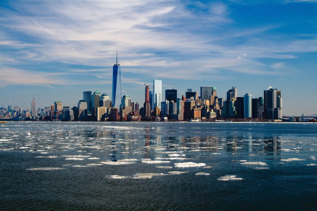 A stunning winter morning captures New York City skyline with icy waters in the foreground.